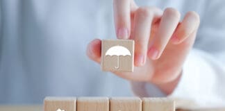 Insurance concept. Protection against a possible eventuality. Hand holding umbrella icon and House, Car, Family and Health icon on wooden block for assurance life concept.