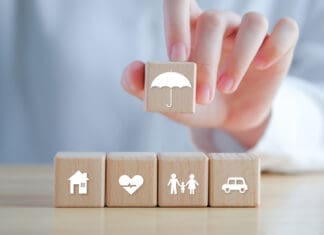 Small Ways to Make Your Insurance Work for You Insurance concept. Protection against a possible eventuality. Hand holding umbrella icon and House, Car, Family and Health icon on wooden block for assurance life concept.