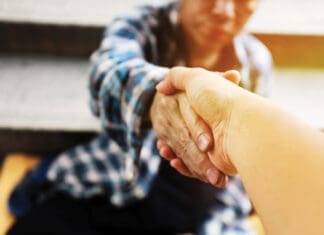 From Hardship to Hope: A Story of Resilience and Renewal Close-up handshake for help homeless man on walking street in the capital city.